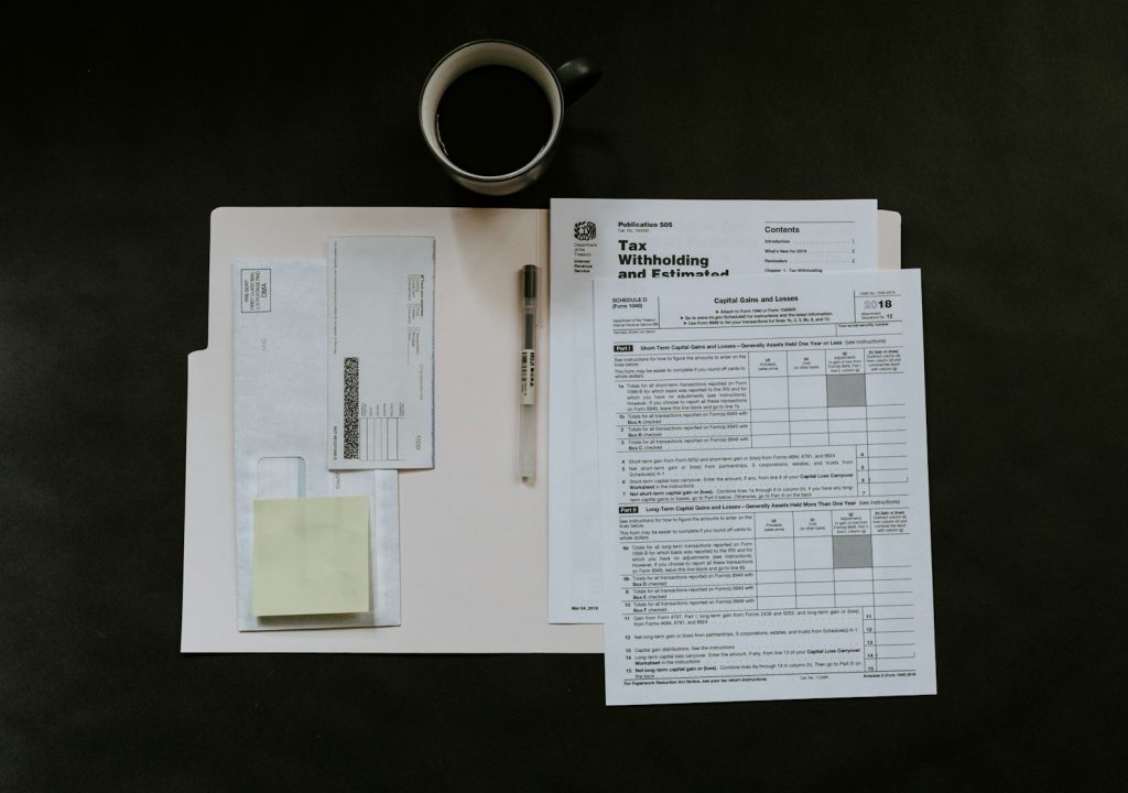 Tax forms, a pen, and a coffee mug on a dark desk